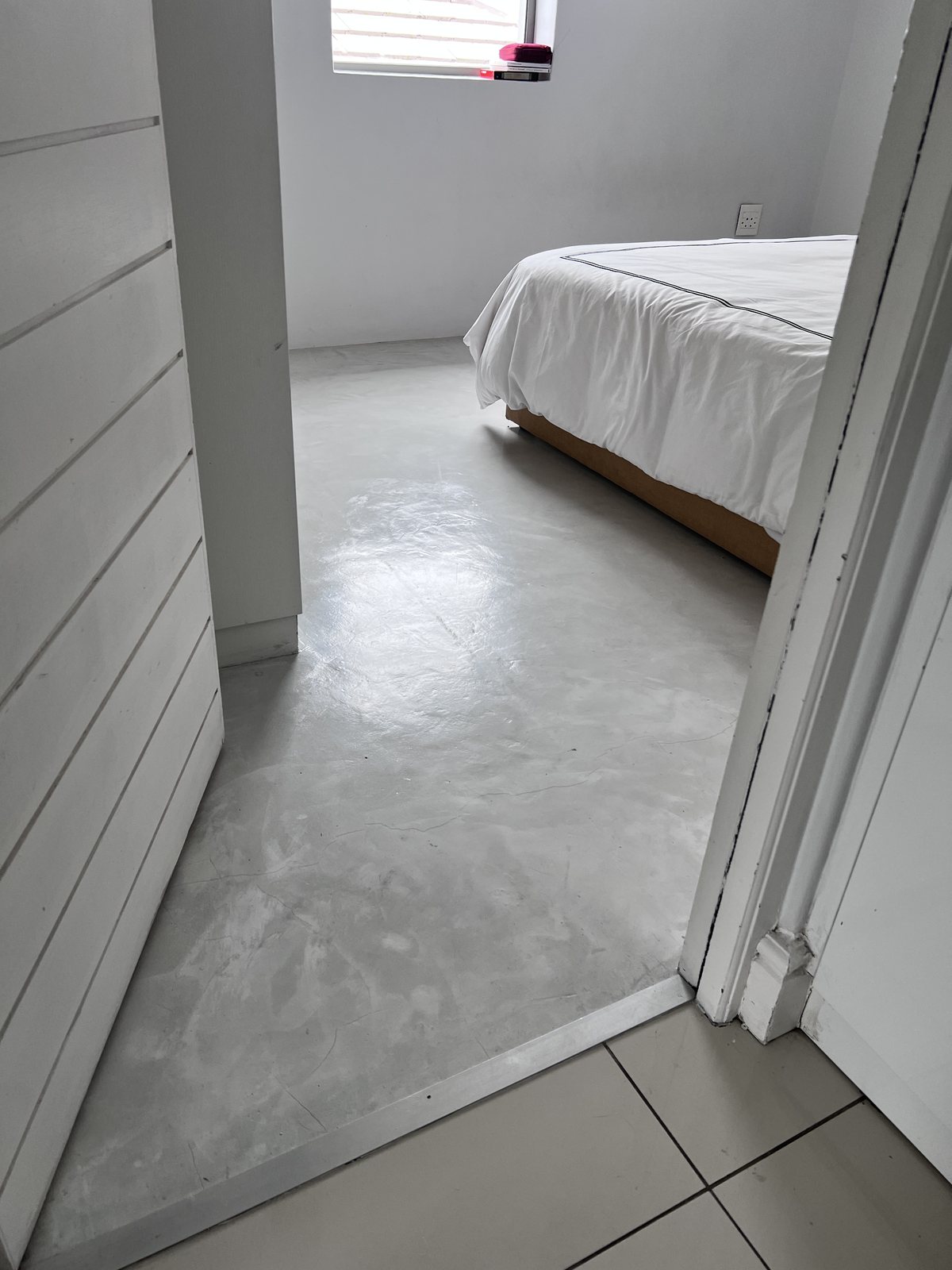 The original cold, grey epoxy floor in the Sunset Beach bedroom before the SPC went down